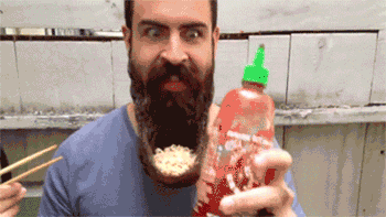 Bearded guy eyeing sriracha bottle with chopsticks ready